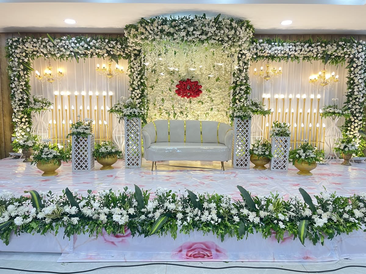 Engagement decoration in Hyderabad with a white and green floral arch, gold candle stands and decorated couple seating