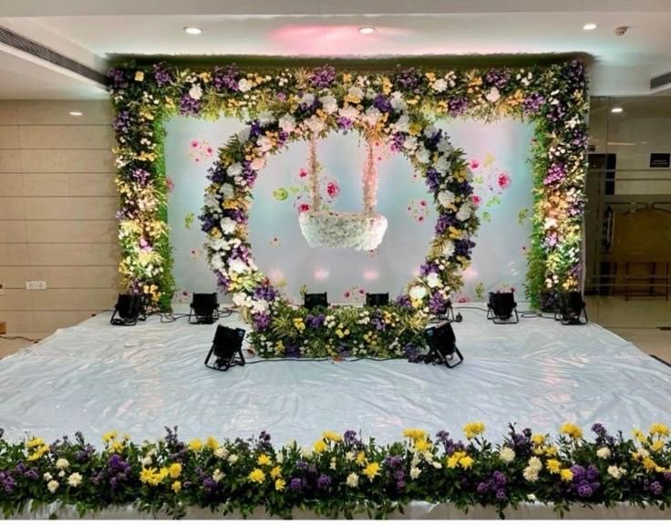 Half saree function decoration in Hyderabad with a floral arch stage, hanging flower swing and a mixed pastel flower border