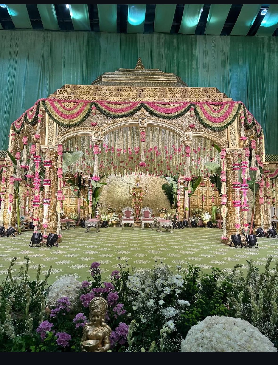Marriage mandap decoration in Hyderabad with a carved gold mandap, pink and white floral garlands and a hanging jasmine canopy