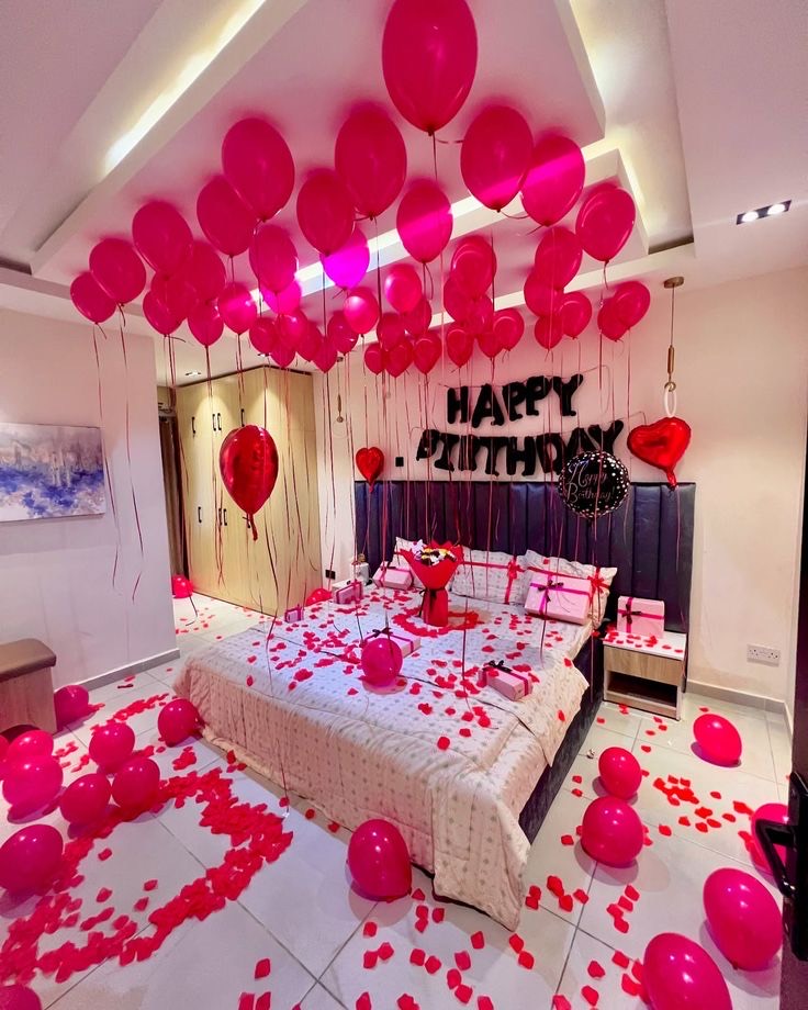 Room surprise decoration in Hyderabad with pink ceiling balloons, a Happy Birthday foil message and rose petals on the bed